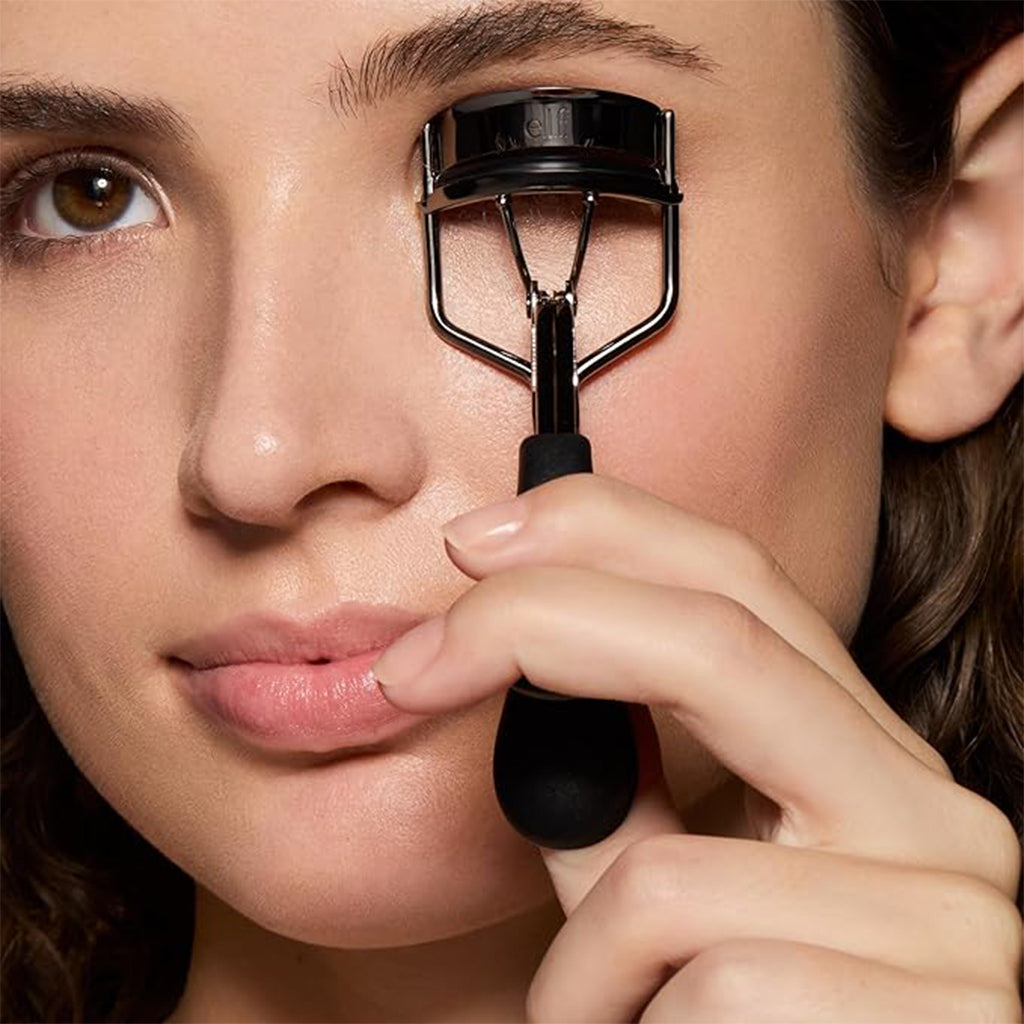 Woman using Aardlig LashCurl eyelash curler for natural, even curls with a comfortable grip.